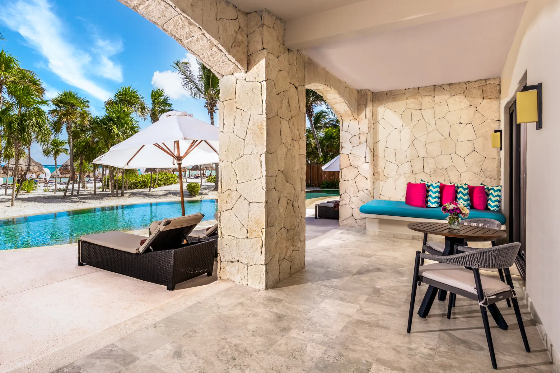 Preferred Club swim-out terrace at Secrets Maroma Beach Riviera Cancun, looking through a stone arch to the pool and Maroma Beach